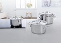 Une cuisine avec plusieurs casseroles en acier inoxydable sur une plaque à induction et un plan de travail.