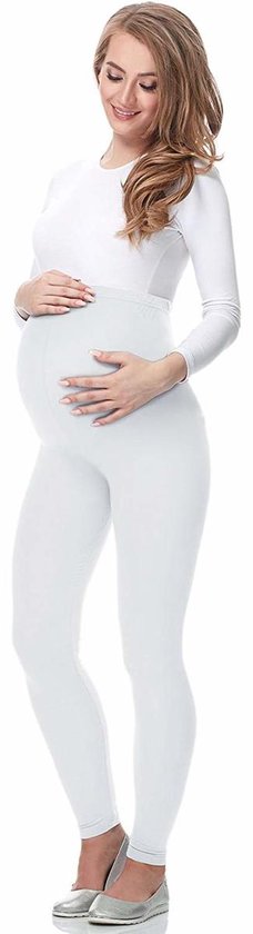 Zwangere vrouw in witte legging en wit shirt, met hand op buik.