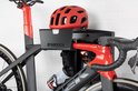 Zwarte en rode racefiets met rode helm en bidon op een Stasdock muurbeugel.