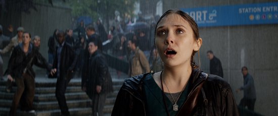 Een jonge vrouw met nat haar en een open mond kijkt omhoog in de regen, met een menigte op de achtergrond.
