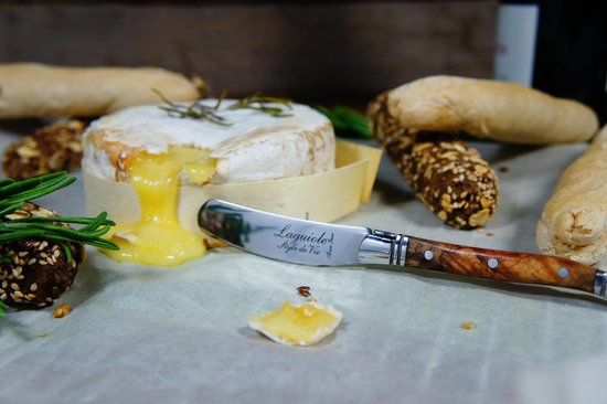Smeltende camembert met een Laguiole botermes met olijfhouten handvat.