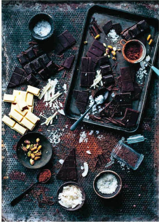 Diverse soorten chocolade, pistachenoten en kokosvlokken op een donkere metalen ondergrond.