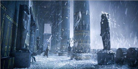 Een man loopt door een duistere tempel met gigantische pilaren. Er valt sneeuw en er staan beelden.