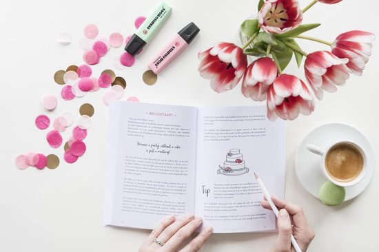 Een open boek met de tekst 'Trouwen doe je zo!', tulip's, confettie, highlighters, koffie en een trouwtaart.
