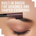 Een close-up van een oog met wenkbrauw, het borsteltje van het wenkbrauwpenseel kamt de wenkbrauw. Tekst: Built-in brush for groomed and shaped eyebrows.