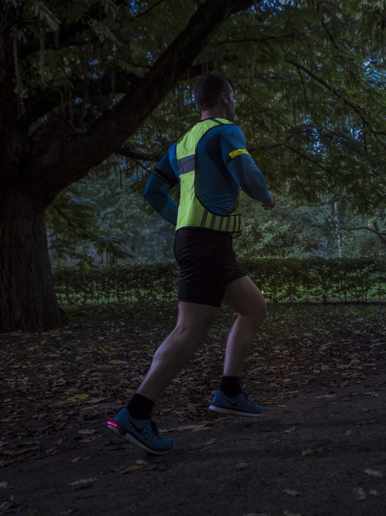 Man joggend in het donker met een fluoriserend geel en blauw sportshirt met reflecterende details.
