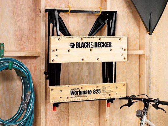 De opvouwbare Black+Decker Workmate 825 werkbank hangt aan een muur in een schuur.