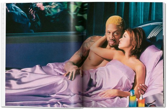 Dennis Rodman met blond haar en een vrouw liggen samen in paars satijnen lakens.