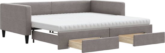 Taupe stoffen slaapbank met uitgetrokken onderschuifbed en twee open lades.