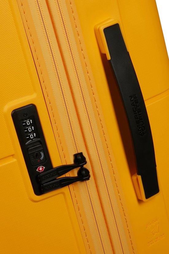 Detail van een gele koffer: TSA-slot en zwarte handgreep.