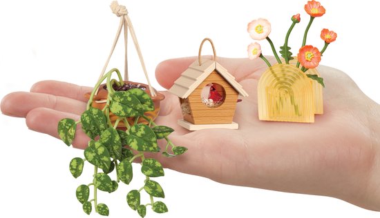 Hangende plant, vogelhuisje met rode vogel en vaas met bloemen in hand.