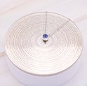 Zilverkleurige ketting met blauwe hanger op een zilveren display.