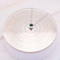Zilverkleurige ketting met groene zirkonia hanger op een zilveren ronde ondergrond met patronen.