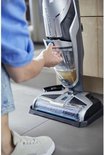 Hand verwijdert vuil water reservoir van een BISSELL Crosswave C3 Select stofzuiger met dweil.