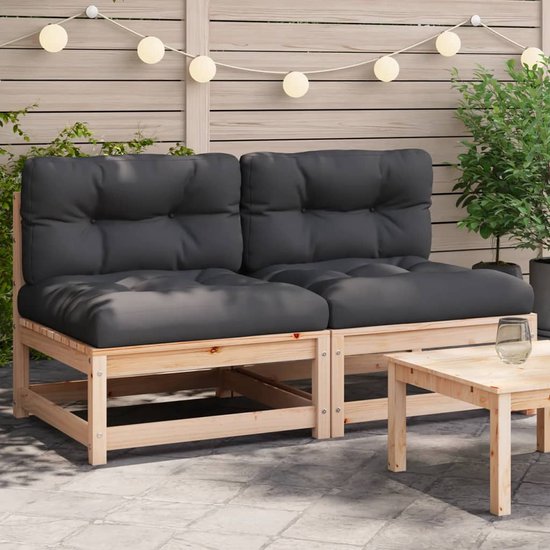 Houten tuinbanken met zwarte kussens en decoratieve lichtjes op de achtergrond.