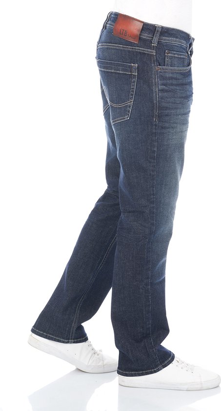 Zijaanzicht van blauwe denim jeans met rechte pijpen en een lichte wassing, gedragen op witte sneakers.