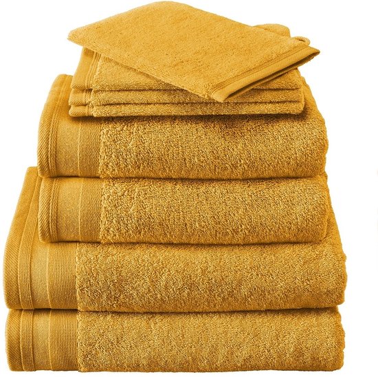 Pile de serviettes jaune moutarde, avec un gant de toilette plié sur le dessus.