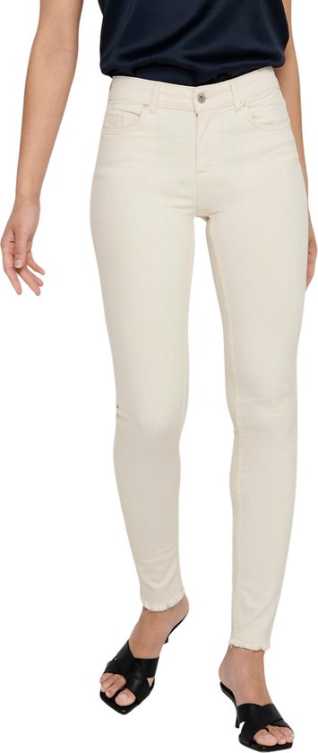 Model in een lichte, skinny jeans met rafels aan de onderkant en zwarte sandalen.