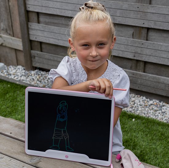Een meisje met blonde staart zit op een picknicktafel en tekent met een roze stylus op een roze tekentablet.
