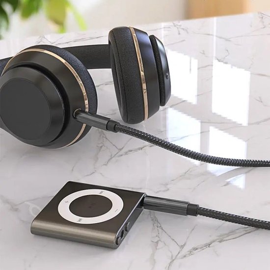 Casque noir avec accents dorés, relié à un petit convertisseur audio argenté avec un cercle blanc.