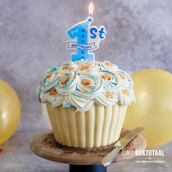 Grote cupcake met witte en blauwe botercrème, gouden kroontjes en een 'My 1st Birthday' kaars.