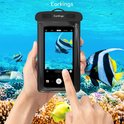 Handen houden waterdichte telefoonhoes, maken foto onder water van vissen. Water en koraal op achtergrond.