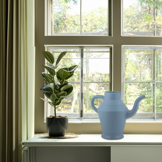 Blauwe kunststof gieter van 2 liter met een gebogen handvat en een lange tuit, naast een plant op een vensterbank.