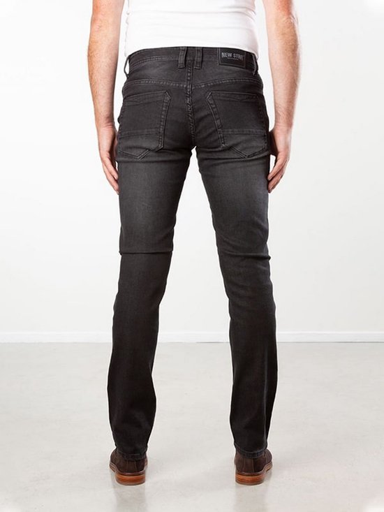 Achterkant van een model in een zwarte, slim fit stretch spijkerbroek met opgestikte achterzakken.