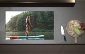 Inductieplaat Beschermer - Blonde Vrouw op Supbord op Water langs Rij Bomen - 85x51 cm - 2 mm Dik - Inductie Beschermer - Bescherming Inductiekookplaat - Kookplaat Beschermer van Zwart Vinyl
