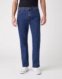 Man in zwart T-shirt en donkerblauwe jeans met witte sneakers.