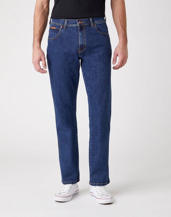 Man in zwart T-shirt en donkerblauwe jeans met witte sneakers.