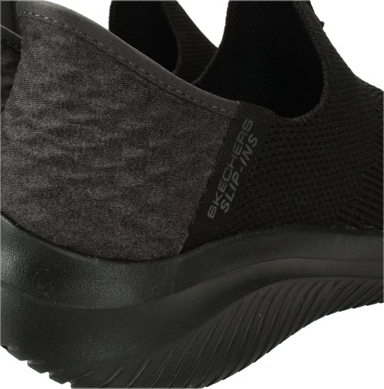 Close-up van de grijze hiel met logo op een zwarte Skechers slip-on sneaker.