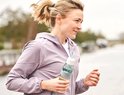 Vrouw in paars jack met een Mepal waterfles met witte dop en grijze band tijdens het sporten.