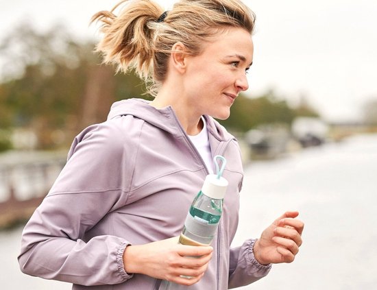 Vrouw in paars jack met een Mepal waterfles met witte dop en grijze band tijdens het sporten.