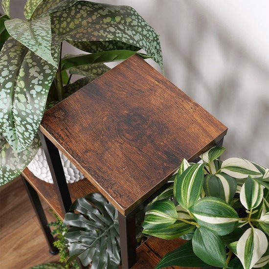 Detailopname van een bruin houten blad van een plantenstandaard met omringende groene bladeren.