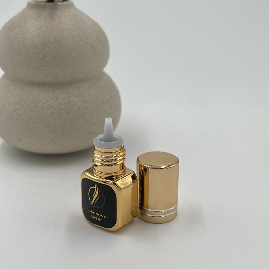 Gouden flesje Lashnovo Expert wimperlijm met dop ernaast.
