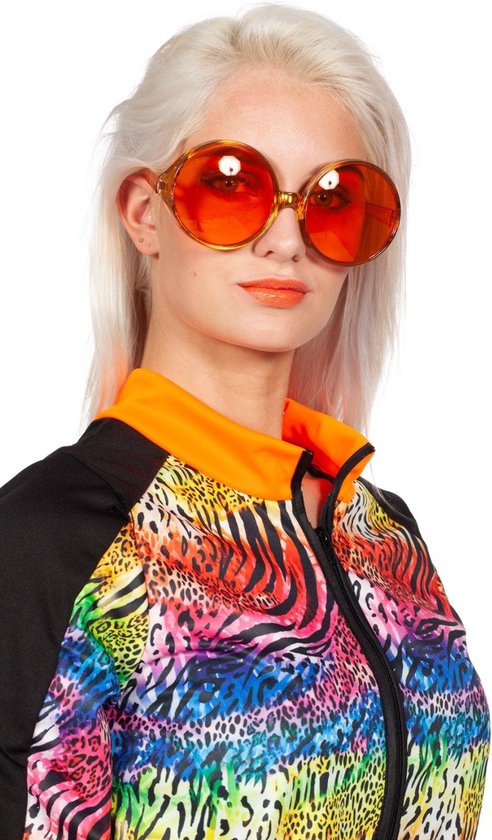 Close-up van vrouw met blonde haren en oranje oversized zonnebril, draagt een kleurrijke trui met dierenprint.