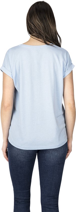 Vrouw draagt lichtblauwe top met opgerolde mouwen en jeans, achterkant.