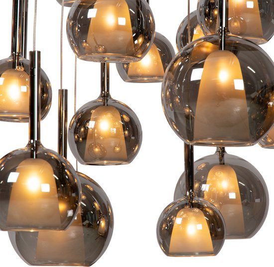 Close-up van verlichte, rookgrijze glazen bollen van een hanglamp tegen een zwarte achtergrond.