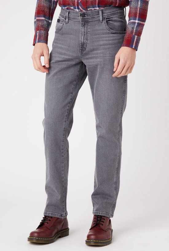 Man met lang blond haar in een grijs straight-fit jeans en een rood geruit flanellen overhemd.