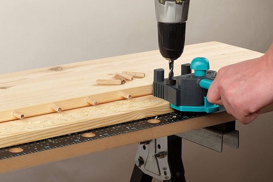 Wolfcraft deuvelmal in gebruik op een houten plank. Deuvels zijn zichtbaar.