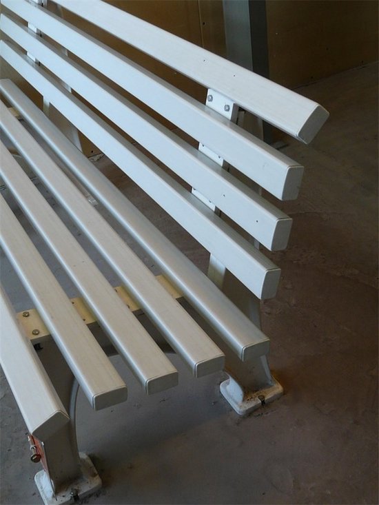 Wit metalen bankje met smalle lamellen.