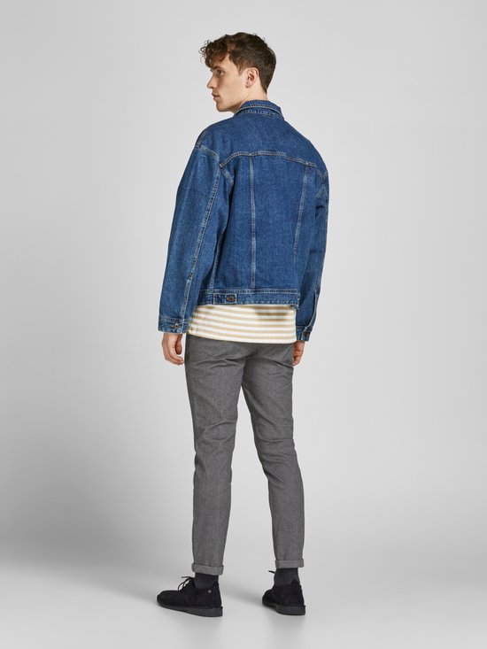 Model van achteren in grijze broek met visgraatpatroon, gestreepte top en spijkerjack.