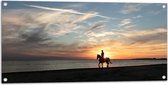 Tuinposter – Paardrijden op het Strand met Zonsondergang - 100x50 cm Foto op Tuinposter (wanddecoratie voor buiten en binnen)