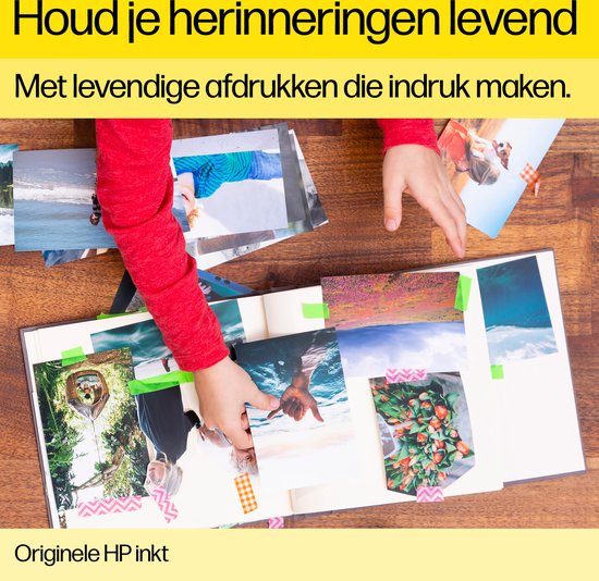 Kinderhand legt foto's in een fotoalbum met washi tape.