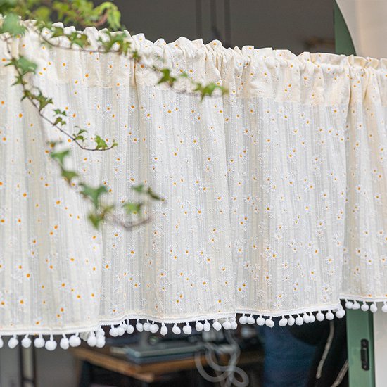 Gordijn valletje met ruches bovenaan en een all-over print van witte madeliefjes met gele hartjes. De onderrand heeft witte pomponnetjes.