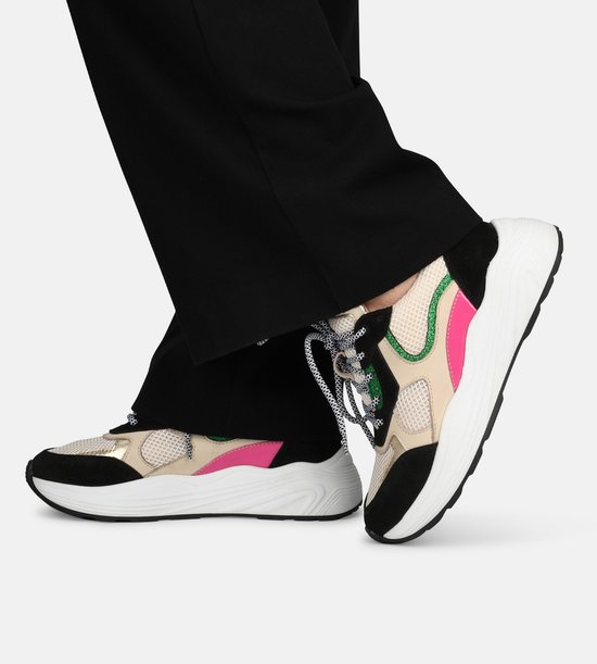 Baskets pour femme avec maille beige, daim noir, accents rose et vert sur une personne.