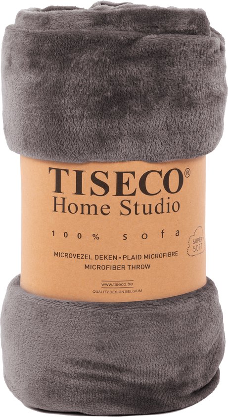 Donkergrijze, opgerolde microvezeldeken met "Tiseco Home Studio 100% SOFA MICROVEZEL DEKEN PLAID MICROFIBRE SUPER SOFT QUALITY DESIGN BELGIUM" op bruine band.