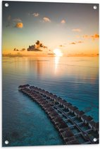 WallClassics - Tuinposter – Rij Vakantiehuisjes op het Water met Ondergaande Zon - 60x80 cm Foto op Tuinposter (wanddecoratie voor buiten en binnen)