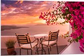 PVC Schuimplaat - Tafel met Stoeljes op Balkon met Roze Bloemenstruik met Uitzicht op Zee - 90x60 cm Foto op PVC Schuimplaat (Met Ophangsysteem)